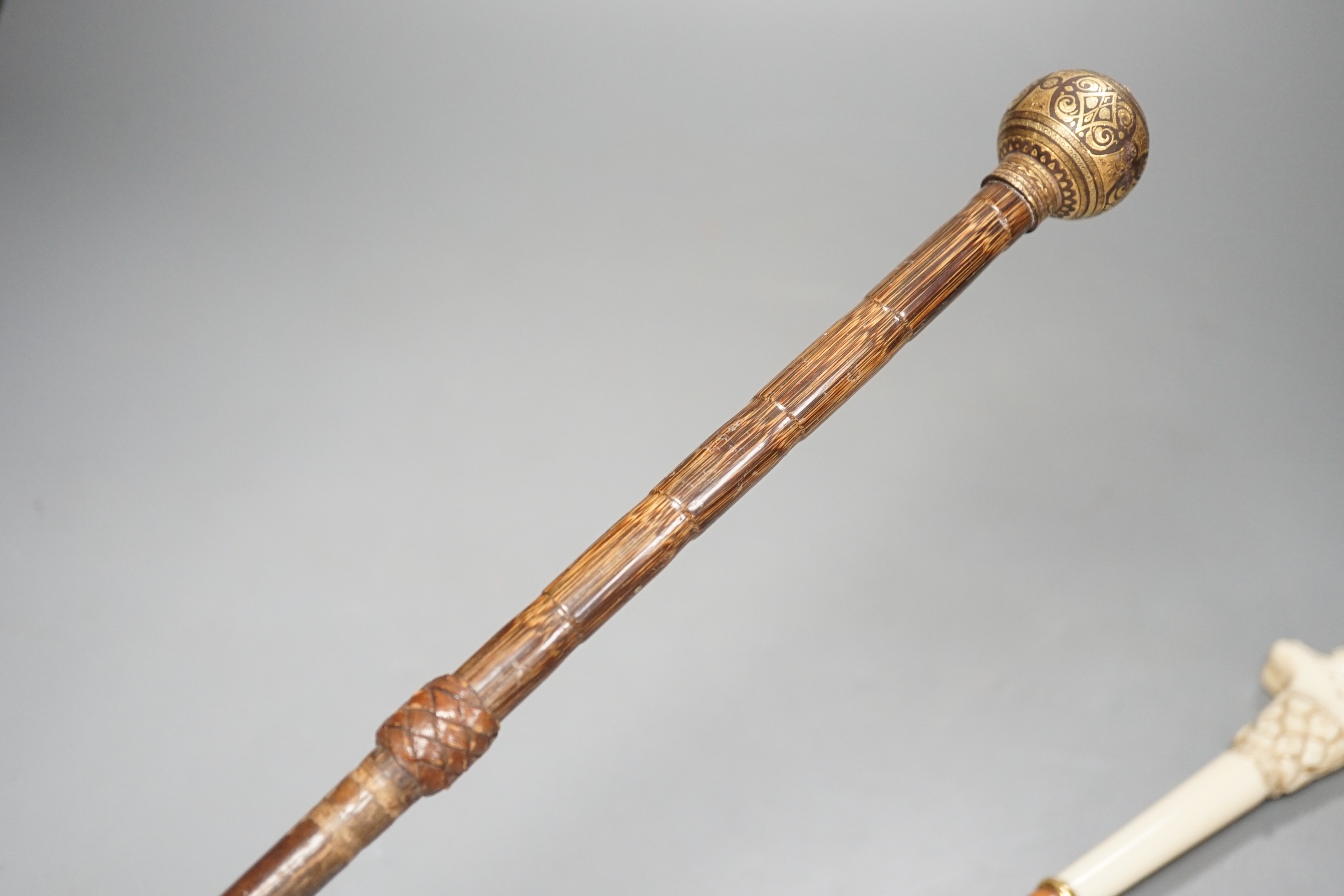 An early 20th century ivory ‘sphinx’ parasol handle, 84cm, together with another gold and iron damascened parasol handle, 62cm